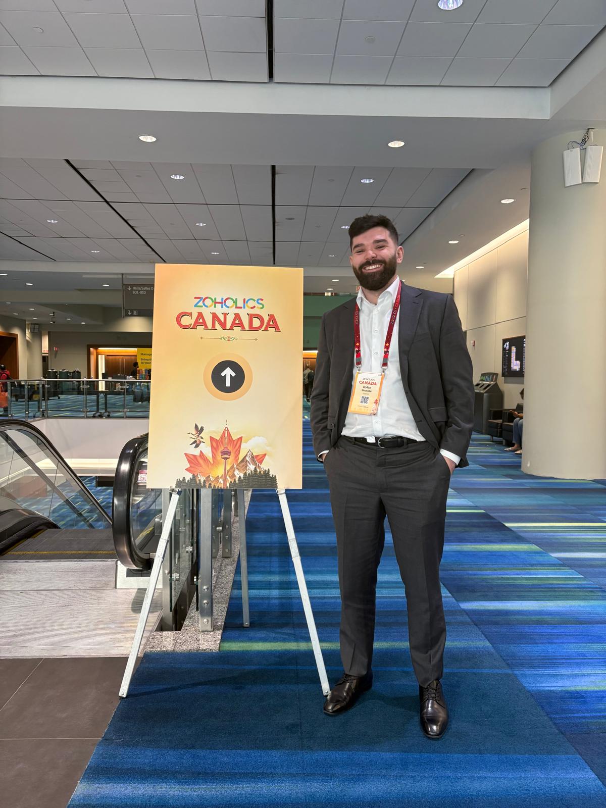 Dylan Shukster beside the Zoholics Canada event sign